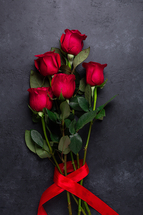 Red rose flowers bouquet on black stone background Valentine's day greeting card Copy space Flat lay